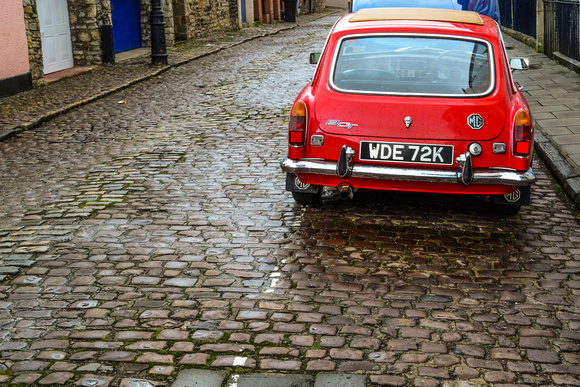 A red MG car against the contrast of a cobbled street